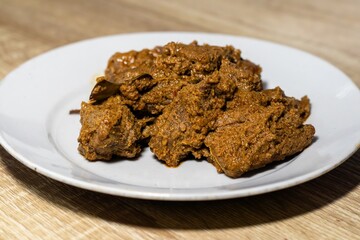 A plate of beef rendang on the wooden table. An Indonesian dish from West Sumatra.