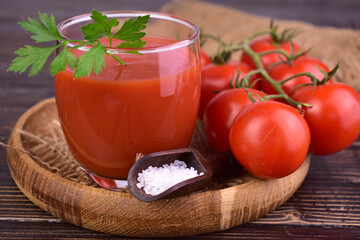 Glass of tomato juice on a dark wooden background. Close-up.

