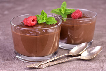 Chocolate mousse with raspberries in glass cups on a gray background.Close-up.
