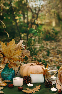 Atmospheric cozy autumn composition. Pumpkins, fall leaves, chestnut, candels. Thanksgiving day. Elegant rustic decor. Concept of cozy fall home atmosphere, aromatherapy. Copyspace.