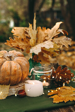 Atmospheric cozy autumn composition. Pumpkins, fall leaves, chestnut, candels. Thanksgiving day. Elegant rustic decor. Concept of cozy fall home atmosphere, aromatherapy. Copyspace.