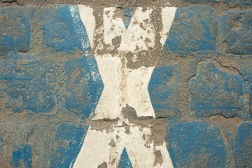 White painted crossed lines on a blue background. Old granite cube, texture, paint, surface, rough, cracked. Design space. Top view.