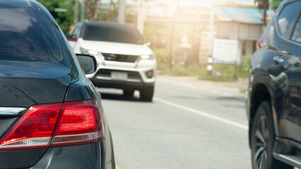 Rear side of dark car with turn on brake light at day time. Cars passing each other on the road.