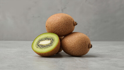 Stack of three whole fuzzy kiwis, one slightly angled, on a polished concrete surface