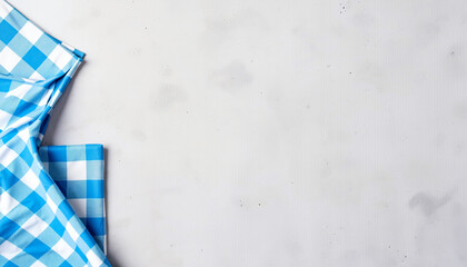 Blue checkered tablecloth draped on gray background for dining setup  