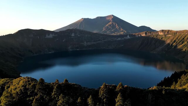 Ascending drone shot reveals a circular caldera lake nestled within ancient, mist-shrouded volcanic peaks at dawn golden, tranquility, adventure