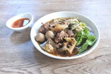 boiled braised beef meat and tendon couple organ in herb brown soup on plate dipping spicy chili sauce 