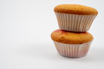 Two plain vanilla cupcakes stacked on white background.
