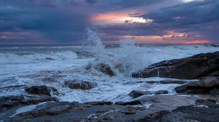 Obraz premium Waves crash on rocks and stir up sediment