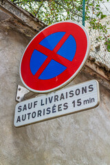 French traffic sign indicating a no stopping zone. The only exceptions are authorized deliveries, which are permitted to stop there for 15 minutes.