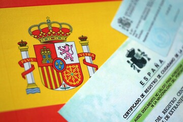 Citizenship or naturalization certificate document and card on flag of Spain close up