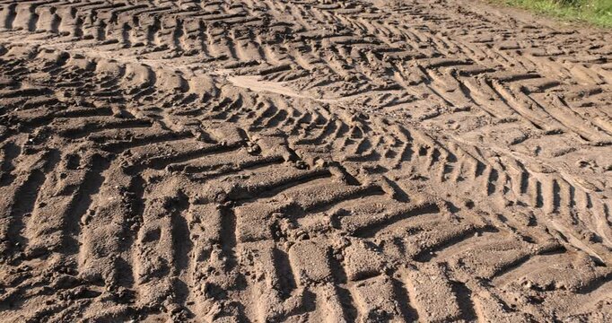 car tracks on the soil in the field, deep tracks from the large tread of very heavy vehicles in the field after harvesting