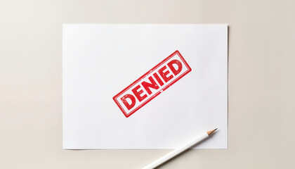Red stamped denial on white paper with pencil on light background  