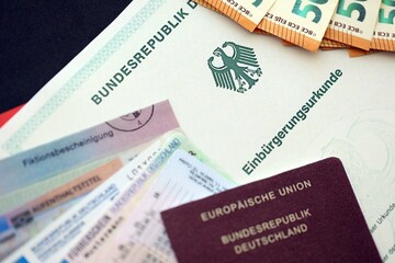 German passport and an identity card on an official naturalization certificate. Symbolic for successful acquisition of German citizenship close up