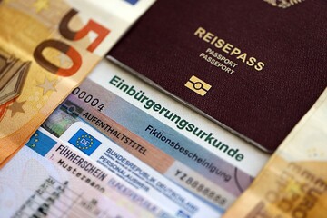 German passport and an identity card on an official naturalization certificate. Symbolic for successful acquisition of German citizenship close up