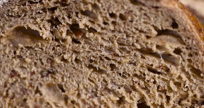 a sliced soft loaf of rye bread on the table on a cutting board, a small elongated loaf of freshly baked rye bread on an old cutting board while slicing bread