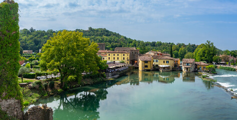 Fototapeta premium Italien, beliebtes Ausflugsziel nähe Gardasee: Der malerische Ort Borghetto bei Valeggio sul Mincio am Fluss - Panorama, Weitwinkelaufnahme