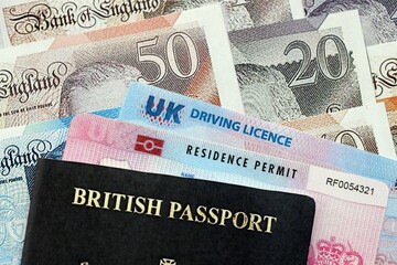 United Kingdom driving license with passport and residence permit card on UK money close up