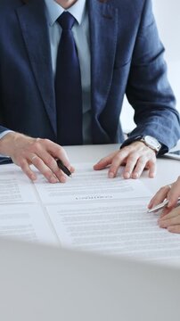 Business colleagues reviewing contract documents during an office meeting, discussing terms, and preparing for agreement signing, focusing on legal consultation and partnership discussion