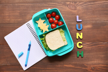Lunch box with tasty food and school stationery on wooden background, top view