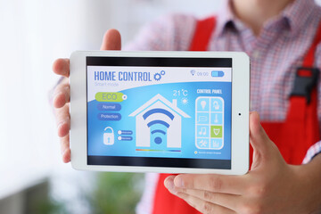Male worker showing tablet with installed alarm security system in house, closeup