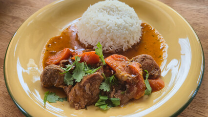 Beef stew with carrots and cilantro served with white rice on plate
