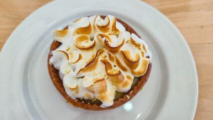 Lemon meringue tart with toasted meringue topping on white plate