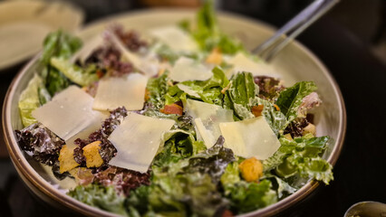 Fresh Caesar salad with lettuce, croutons, and shaved cheese in bowl