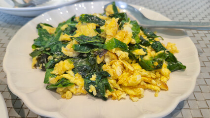 Scrambled eggs with spinach served on white plate for healthy breakfast