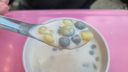 Bua Loi, Thai dessert Spoonful of traditional dessert with taro balls and sweet soup in bowl