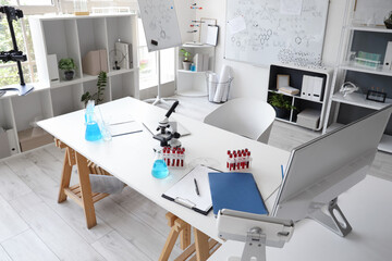 Chemical glassware, test tubes and clipboard on table in medical laboratory