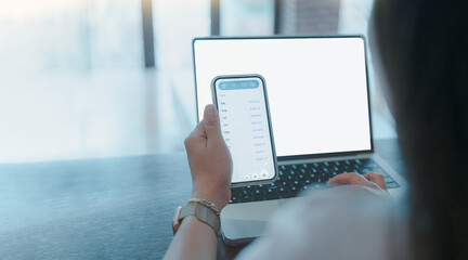 Businesswoman checking monthly income report on smartphone while working on laptop.Person holding mobile phone for digital banking,online financial data analysis,remote work,finance, onlin payment