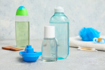 Bottles of cosmetic products for children and boat toy on grunge background, closeup
