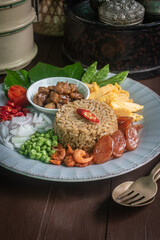Beautifully arranged Thai shrimp paste fried rice, known as Khao Kluk Kapi, served with traditional side ingredients such as sweet pork, sliced omelet, red chili, shallots, dried shrimp, green beans, 