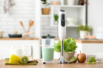 Blender with tasty smoothie and ingredients on table in kitchen