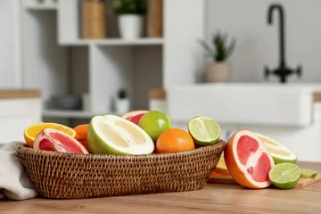 Fototapete Zu Essen Basket with tasty citrus fruits on table in kitchen, closeup  © Pixel-Shot