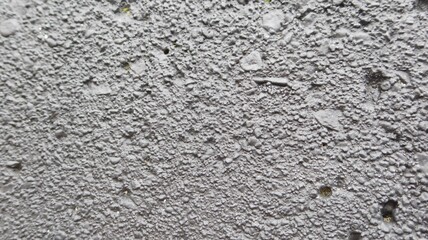 close up rugged uneven wall with lots of holes painted in vibrant grey for wallpaper