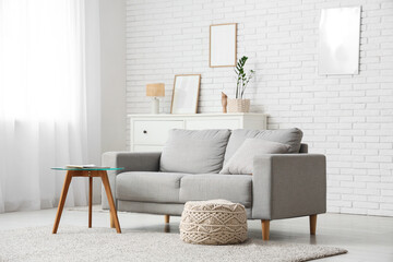 Interior of modern living room with sofa and pouf near window