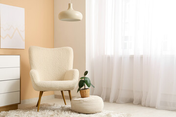 Interior of living room with armchair and pouf near window with curtains
