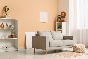 Interior of living room with sofa and pouf near beige wall