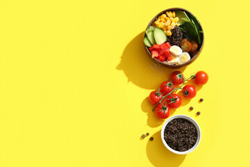 Bowls with healthy quinoa salad and ingredients on yellow background