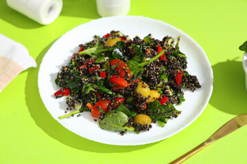 Healthy quinoa bowl with vegetables on green background, closeup