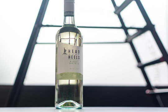 Tall glass bottle of Head Over Heels Pinot Grigio wine by Berton Vineyards against strongly backlit, abstract background of geometric metal structure. Ukraine, Zhytomyr, October, 16, 2025