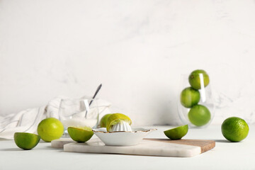 Marble tray, ripe limes and ceramic juicer on white background