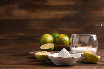 Ceramic juicer with fresh lime on wooden background