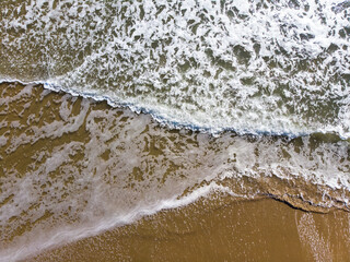 Ocean waves on the beach as a wallpaper background. Beautiful natural summer vacation holidays background. Top down view of beach and sea with blue water waves.