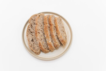 pane di cereali e segale a fette su un piccolo piatto in ceramica su fondo bianco visto da sopra