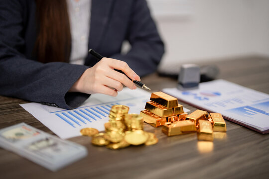 Adult Asian professional reviews gold investment financial data on office desk make strategic trading decisions wealth growth