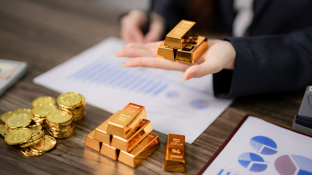 Adult Asian hand gold bars investment portfolio growth strategy financial assets analysis wealth management future planning global market