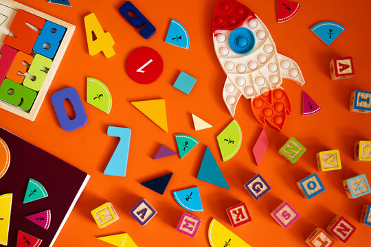 A playful educational setup with colorful numbers, fraction pieces, and a rocket-shaped toy on a brown surface. Bright blocks and learning tools encourage math fun and creativity for kids.